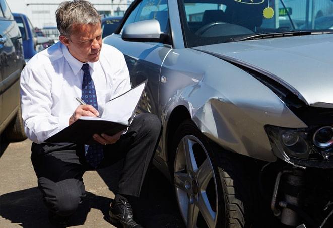 person holding car insurance card with vehicle in background